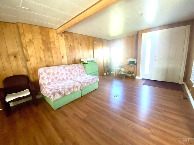 bedroom with wooden walls, hardwood / wood-style floors, and beamed ceiling