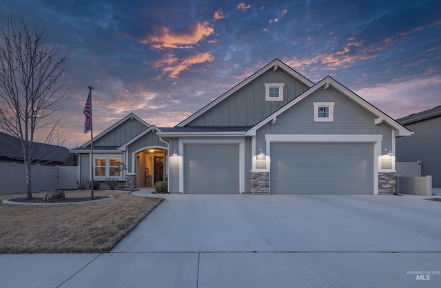 craftsman house with stone siding, fence, board and batten siding, concrete driveway, and a garage