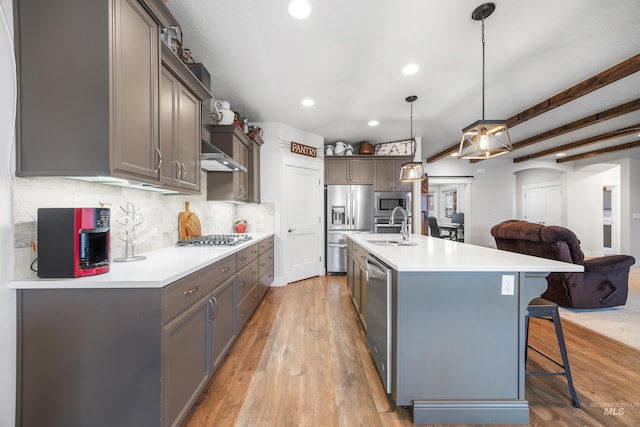 kitchen featuring a breakfast bar area, light wood-style flooring, a sink, decorative backsplash, and stainless steel appliances