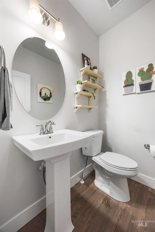 bathroom featuring visible vents, toilet, baseboards, and wood finished floors