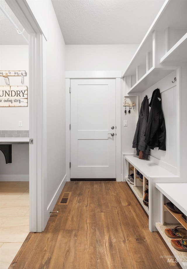 mudroom with visible vents, baseboards, and wood finished floors