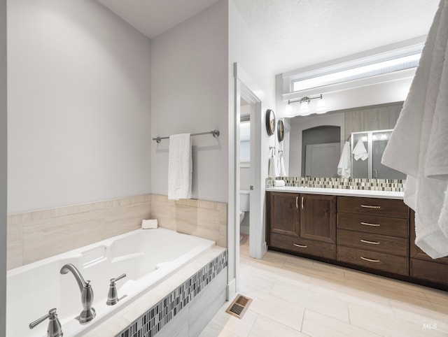 bathroom with visible vents, a garden tub, vanity, and toilet