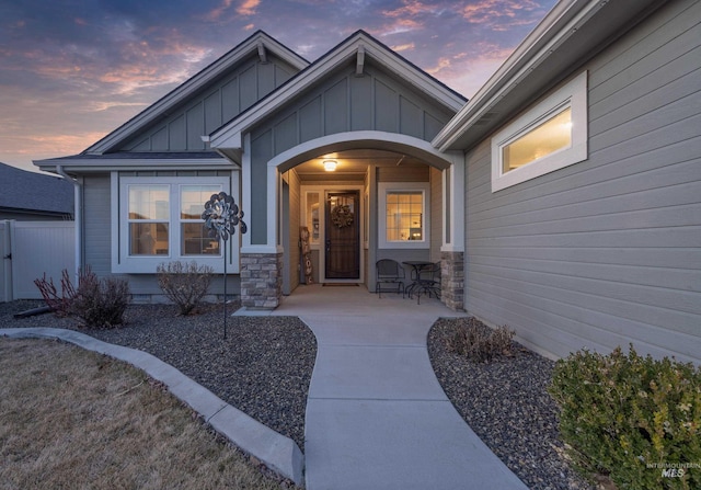 entrance to property featuring a porch, board and batten siding, and fence