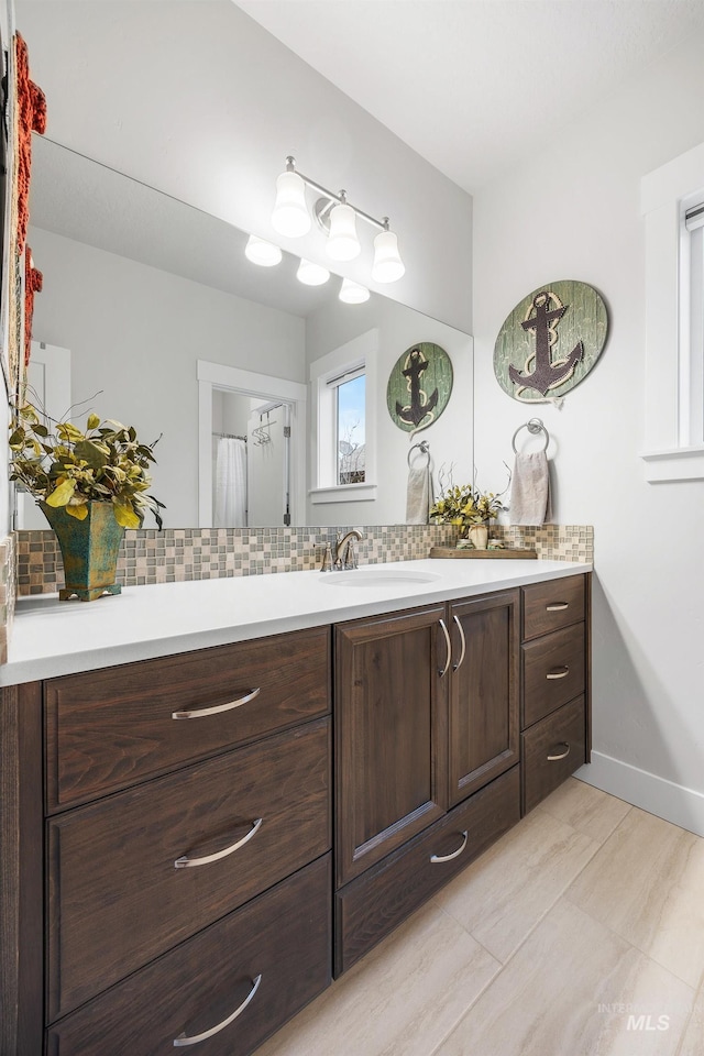 bathroom featuring baseboards, tasteful backsplash, and vanity