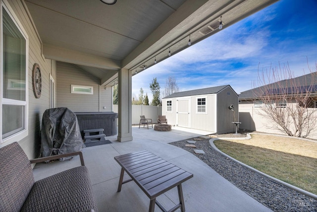 view of patio featuring an outbuilding, an outdoor fire pit, a fenced backyard, a hot tub, and a storage unit