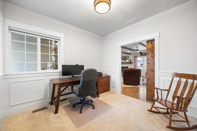 office area featuring visible vents, a textured ceiling, a fireplace, and a decorative wall