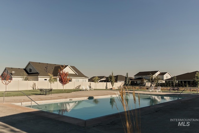 community pool featuring a residential view, a fenced backyard, and a patio area