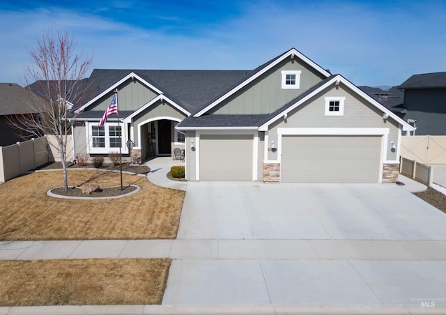 craftsman-style house with stone siding, board and batten siding, driveway, and fence