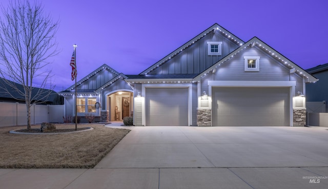 view of front of property featuring stone siding, fence, board and batten siding, and driveway