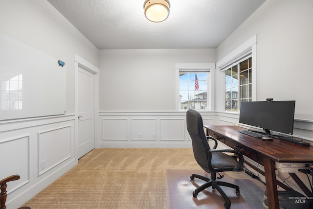 office featuring wainscoting, a decorative wall, light colored carpet, and a textured ceiling