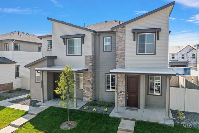 view of front of property featuring stone siding, a front yard, fence, and a residential view