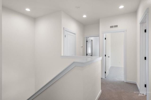 hall featuring light carpet, baseboards, visible vents, and recessed lighting