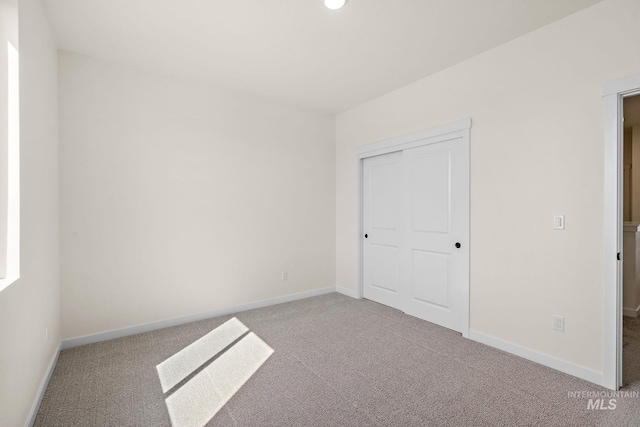 unfurnished bedroom featuring carpet, baseboards, and a closet