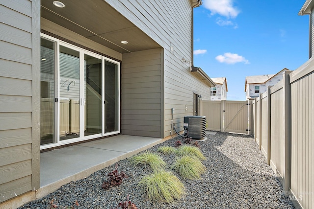 view of side of home with central AC, a patio area, fence, and a gate