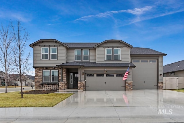 view of front of home with stone siding, a front lawn, concrete driveway, and fence