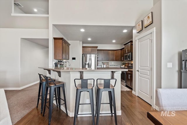 kitchen featuring a peninsula, visible vents, appliances with stainless steel finishes, and a breakfast bar