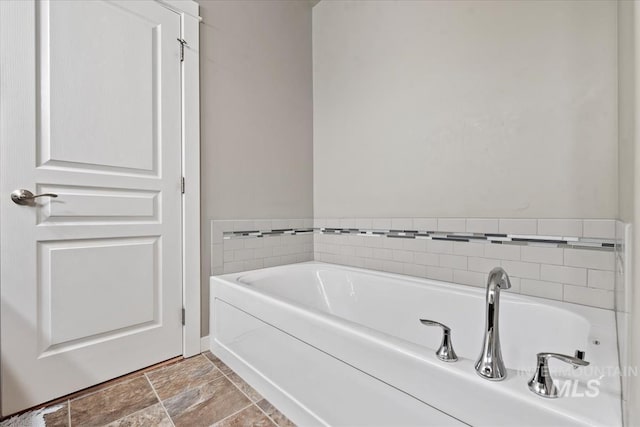 full bath with stone finish floor and a bath