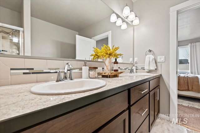 ensuite bathroom featuring connected bathroom, a sink, and backsplash