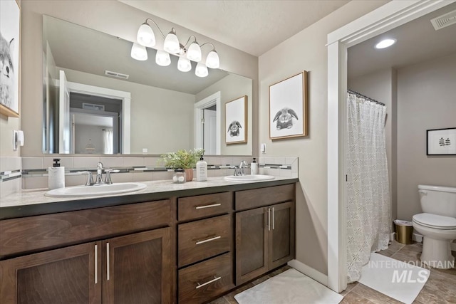 bathroom with toilet, visible vents, and a sink