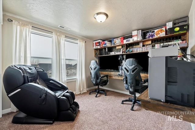 carpeted home office with visible vents, a textured ceiling, and baseboards