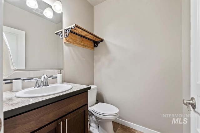 half bathroom featuring tile patterned flooring, toilet, visible vents, vanity, and baseboards