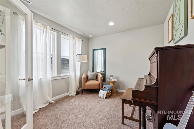 sitting room with visible vents, a textured ceiling, baseboards, and carpet flooring