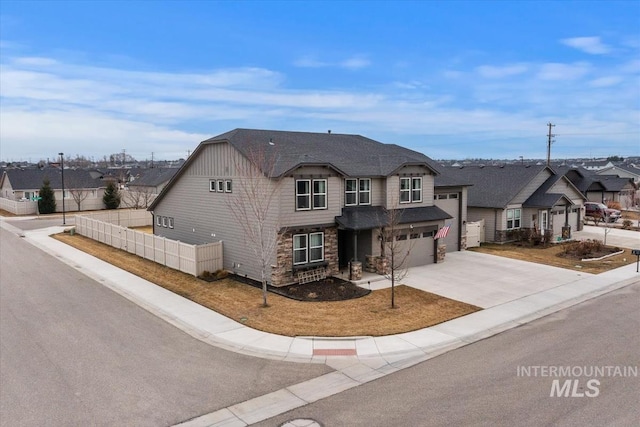 view of front of property featuring an attached garage, fence, a residential view, stone siding, and driveway