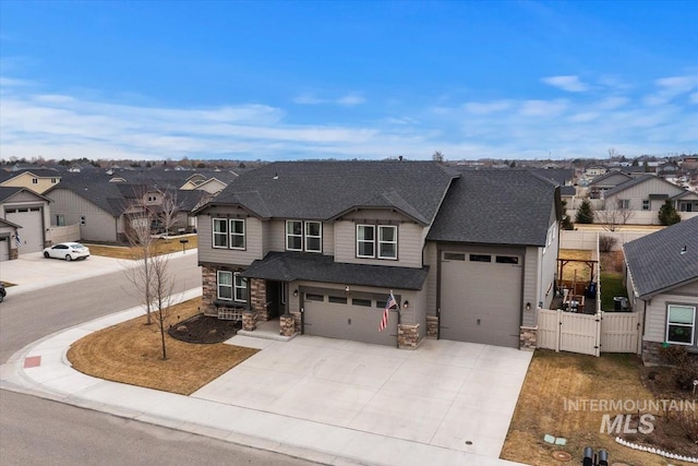 view of front of house featuring driveway, stone siding, a residential view, and a gate