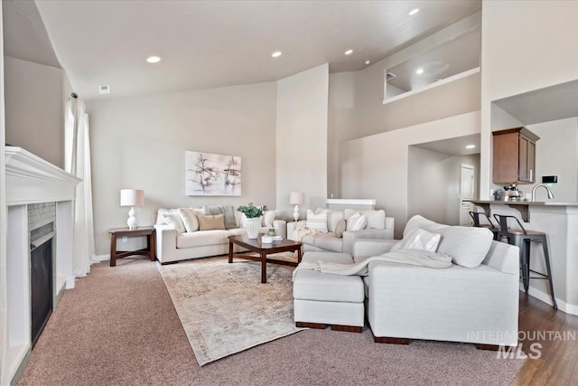 living room featuring high vaulted ceiling, recessed lighting, a fireplace, and baseboards