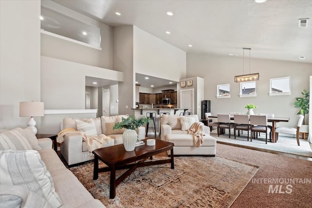 carpeted living room featuring high vaulted ceiling, visible vents, and recessed lighting