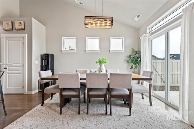 dining room featuring visible vents, vaulted ceiling, baseboards, and wood finished floors