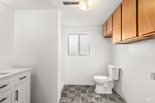 bathroom with vanity, toilet, and a textured ceiling