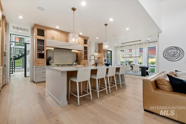 6162 N High Valley Way, Boise, ID 83714 - kitchen featuring light wood-style floors, a large island with sink, decorative backsplash, recessed lighting, and light countertops
