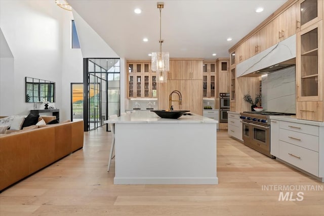 6162 N High Valley Way, Boise, ID 83714 - kitchen featuring stainless steel appliances, a sink, a kitchen island with sink, light countertops, and glass insert cabinets