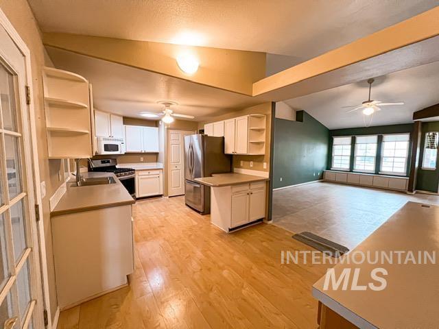 kitchen featuring light wood-type flooring, kitchen peninsula, stainless steel fridge, vaulted ceiling, and a kitchen bar