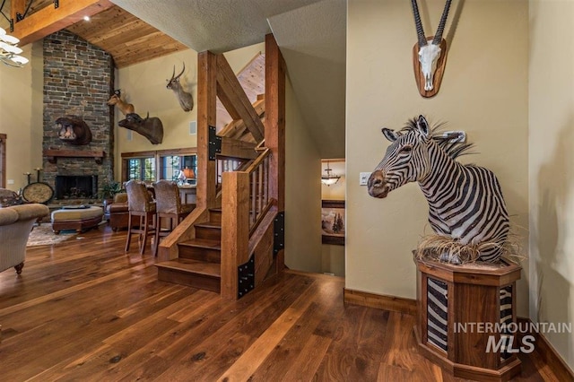 516 Whitewater Dr, Donnelly, ID 83615 - stairs with dark hardwood / wood-style flooring, beamed ceiling, high vaulted ceiling, an inviting chandelier, and a stone fireplace