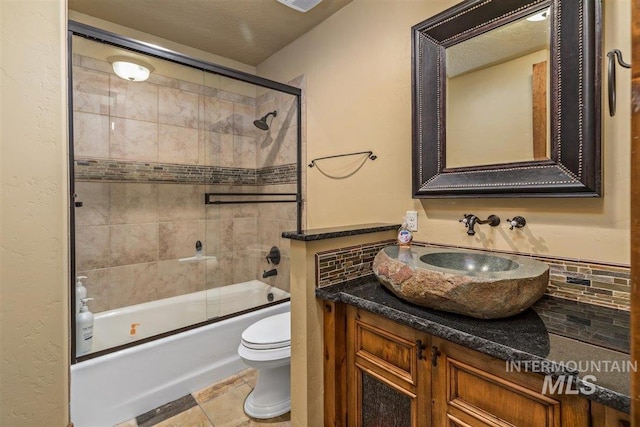 516 Whitewater Dr, Donnelly, ID 83615 - full bathroom featuring toilet, vanity, backsplash, tile flooring, and bath / shower combo with glass door