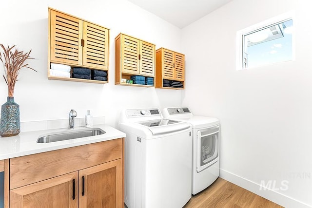 3012 E Parulo Dr, Meridian, ID 83642 - laundry area featuring a sink, light wood-type flooring, washing machine and clothes dryer, baseboards, and cabinet space