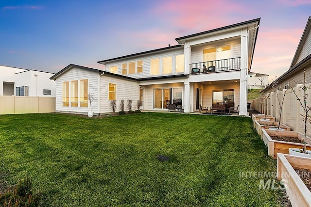 3012 E Parulo Dr, Meridian, ID 83642 - back of house at dusk featuring a yard, a vegetable garden, a fenced backyard, and a balcony