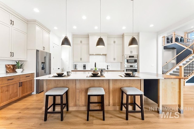 3012 E Parulo Dr, Meridian, ID 83642 - kitchen featuring backsplash, light wood-style flooring, appliances with stainless steel finishes, and a breakfast bar area