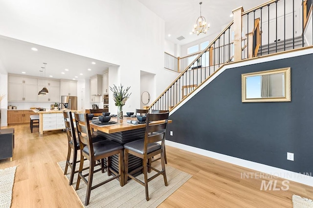 3012 E Parulo Dr, Meridian, ID 83642 - dining space with light wood-style flooring, recessed lighting, an inviting chandelier, a high ceiling, and stairs