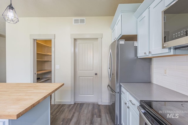 11965 Goldfinch St, Caldwell, ID 83605 - kitchen with stainless steel microwave, butcher block countertops, dark wood-style flooring, white cabinets, and tasteful backsplash