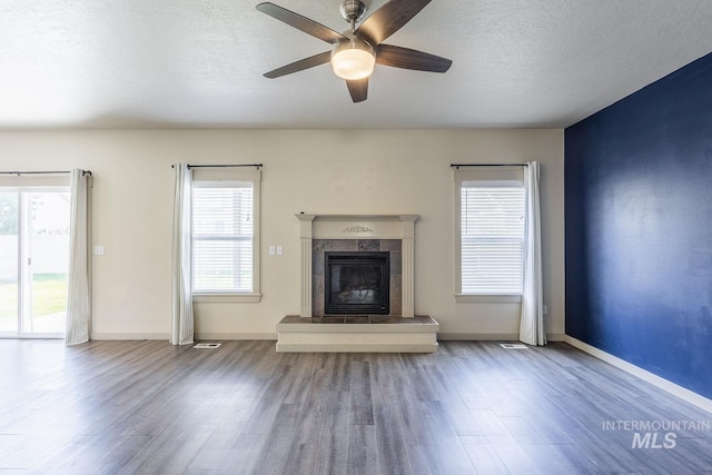 11965 Goldfinch St, Caldwell, ID 83605 - unfurnished living room featuring wood finished floors, a ceiling fan, a textured ceiling, a tiled fireplace, and baseboards