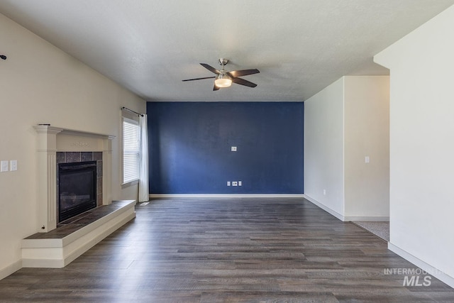 11965 Goldfinch St, Caldwell, ID 83605 - unfurnished living room featuring a ceiling fan, wood finished floors, a tiled fireplace, and baseboards