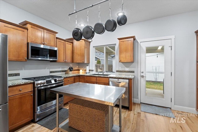 2315 N 22nd St, Boise, ID 83702 - kitchen with light wood-type flooring, a sink, appliances with stainless steel finishes, and brown cabinets