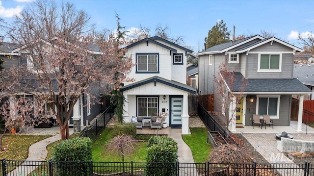 2315 N 22nd St, Boise, ID 83702 - view of front of house featuring roof with shingles, a fenced front yard, an outdoor living space with a fire pit, board and batten siding, and a patio area
