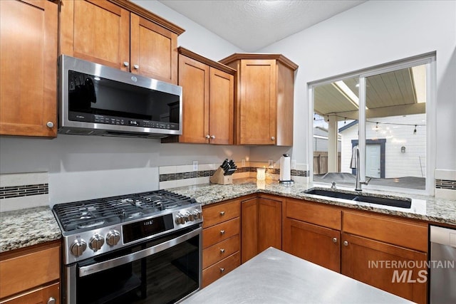 2315 N 22nd St, Boise, ID 83702 - kitchen with appliances with stainless steel finishes, brown cabinetry, a sink, and light stone counters
