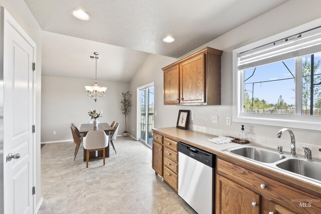 kitchen featuring stainless steel dishwasher, brown cabinets, a healthy amount of sunlight, and lofted ceiling