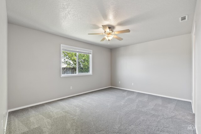 carpeted spare room with visible vents, a textured ceiling, baseboards, and ceiling fan