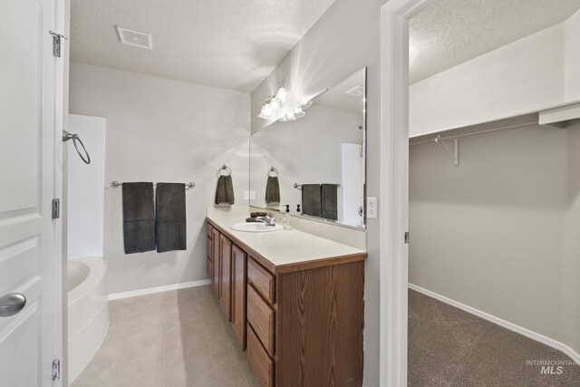 full bath with visible vents, vanity, baseboards, a textured ceiling, and shower / bath combination